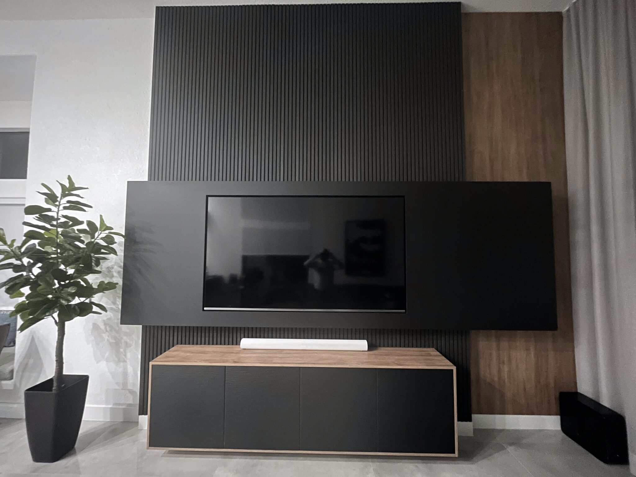 Modern custom entertainment wall with mounted TV, vertical paneling, and storage
